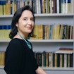 A photo of Pilar Cossio sitting in front of a shelf of math books.