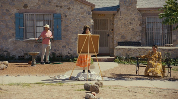 Person standing in front of window; person standing at an easel; woman sitting on a bench