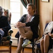 Three people sitting on chairs in and part of group discussion.