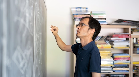 A portrait of Terry Tao near a chalkboard, taken at UCLA.