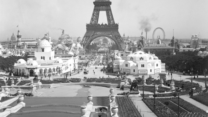 Black and white photo of the Eiffel Tower with a ferris wheel in the background.