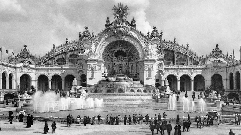 A view of water fountains in front of a grand and ornately carved building.
