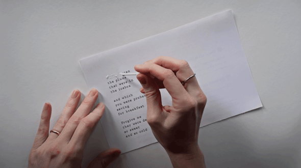 Two hands, one holding a paper while the other applies whiteout to text set like a poem.
